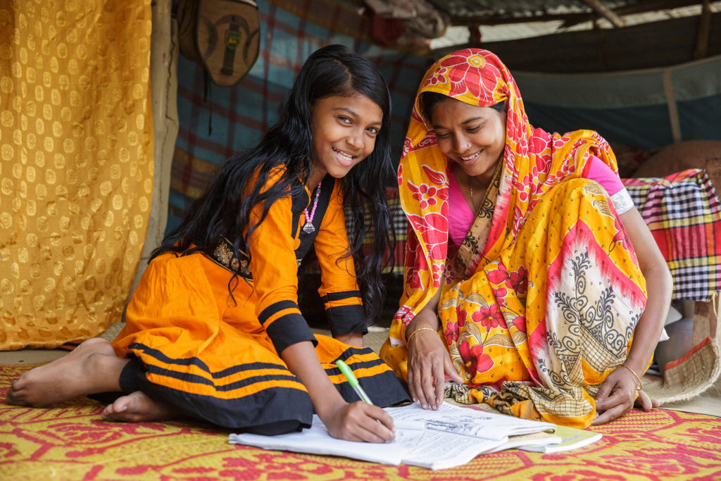 Hasina Begum, 27, helps her daughter Shopna Khatun, 10, do her homework.